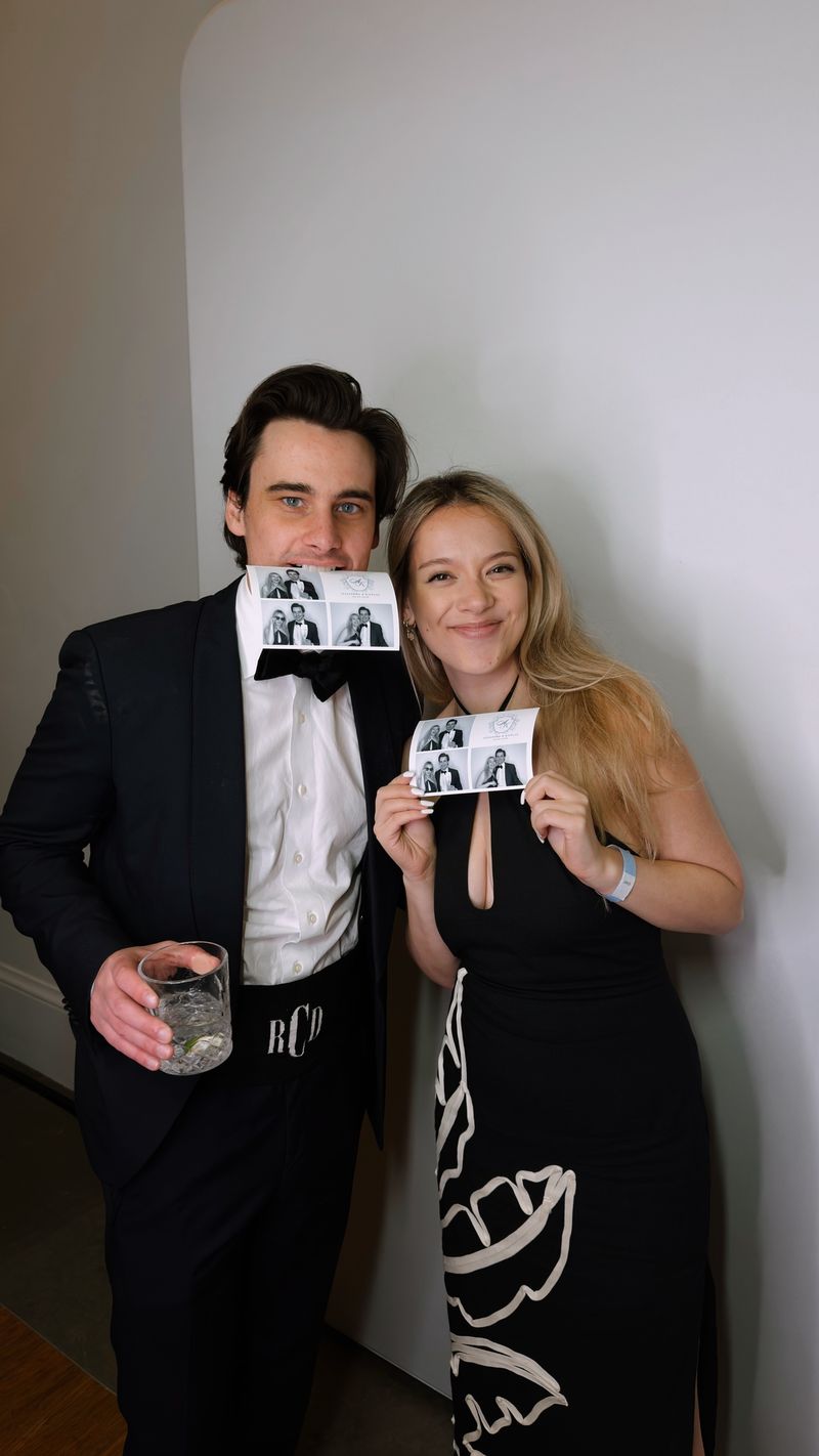 Guests in black tie showing off their photo booth prints