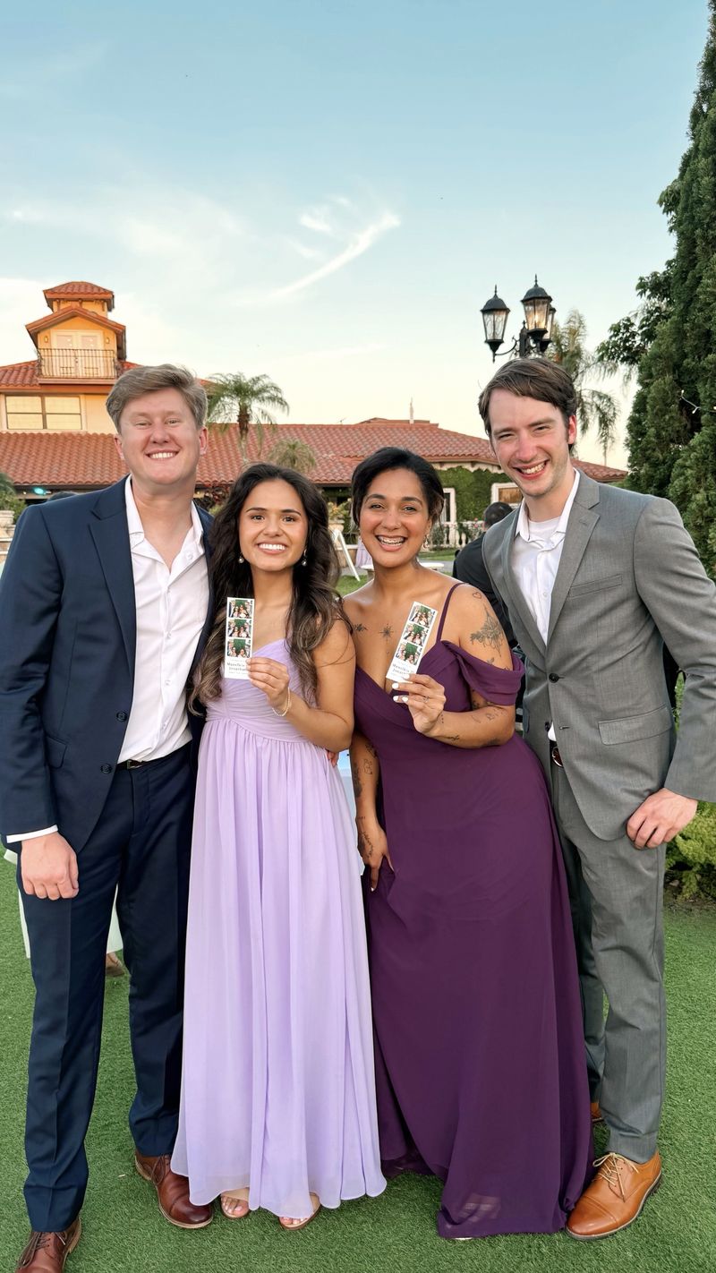 Wedding party holding photo strips outdoors at sunset