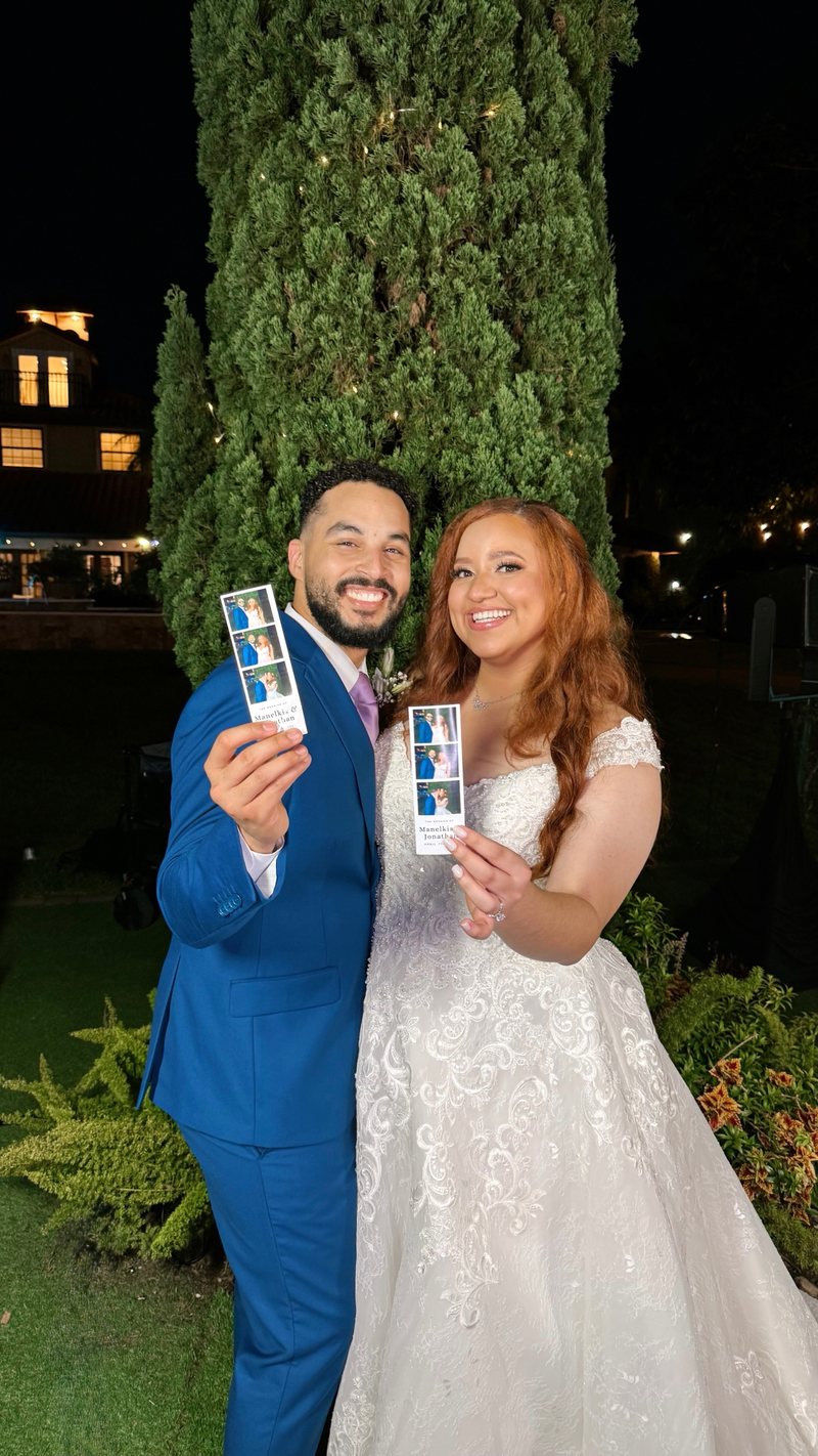Newlyweds holding up their photo strips at night